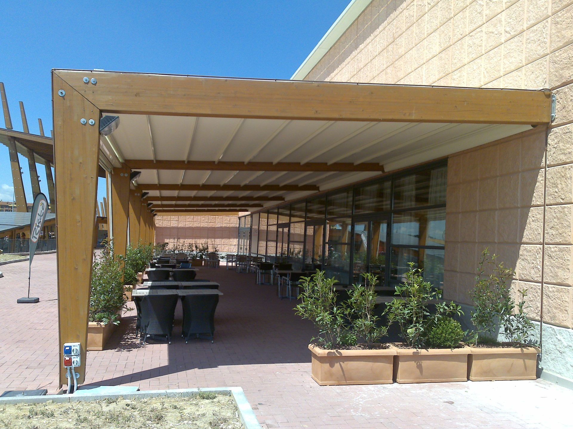 A brick building with a wooden pergola over it - Freehold, NJ - Awning Design Inc