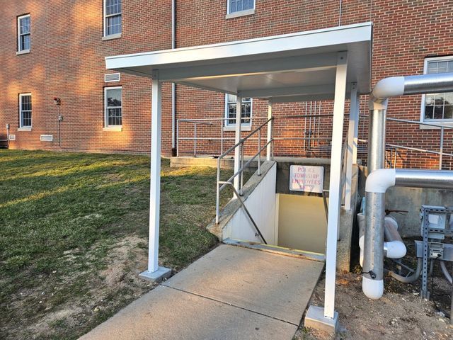 A brick building with a covered walkway leading to a basement - Freehold, NJ - Awning Design Inc