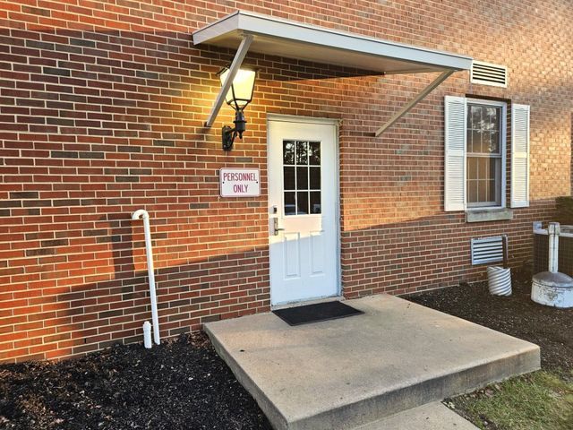 A brick building with a white door and a canopy over it - Freehold, NJ - Awning Design Inc