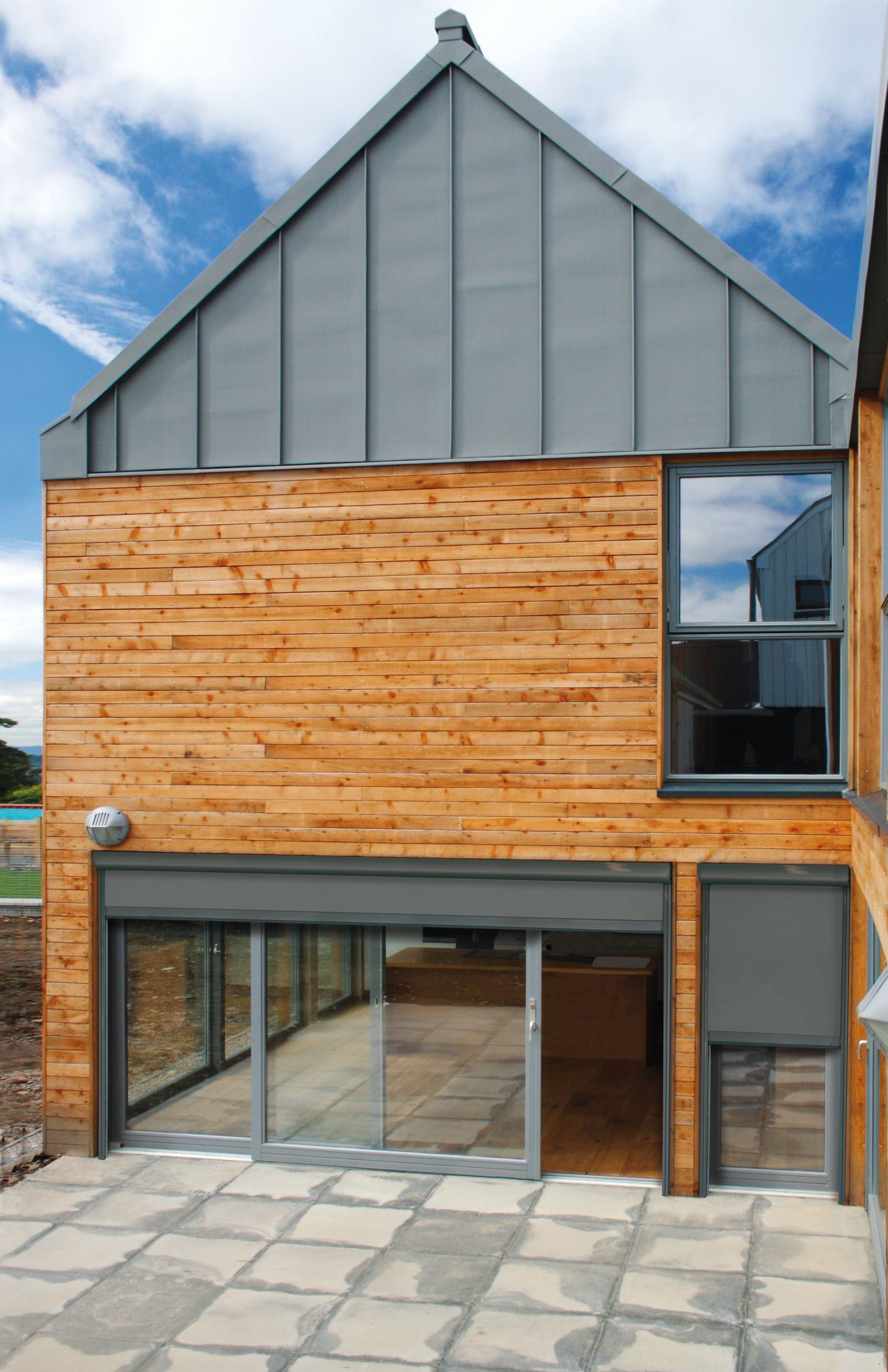 A wooden house with a gray roof and sliding glass doors - Freehold, NJ - Awning Design Inc
