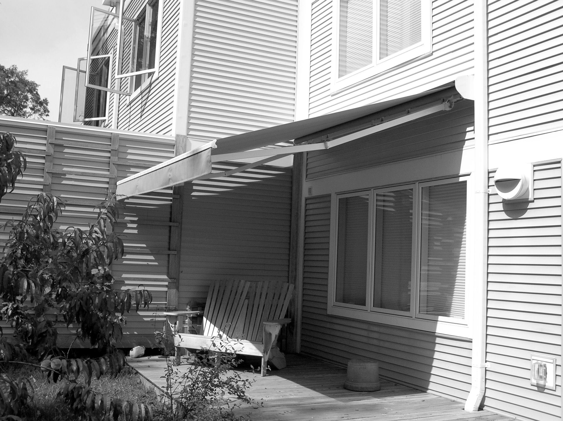 A black and white photo of a house with a patio area - Freehold, NJ - Awning Design Inc