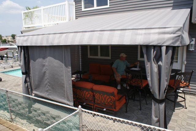 A man is standing under a canopy in front of a house - Freehold, NJ - Awning Design Inc