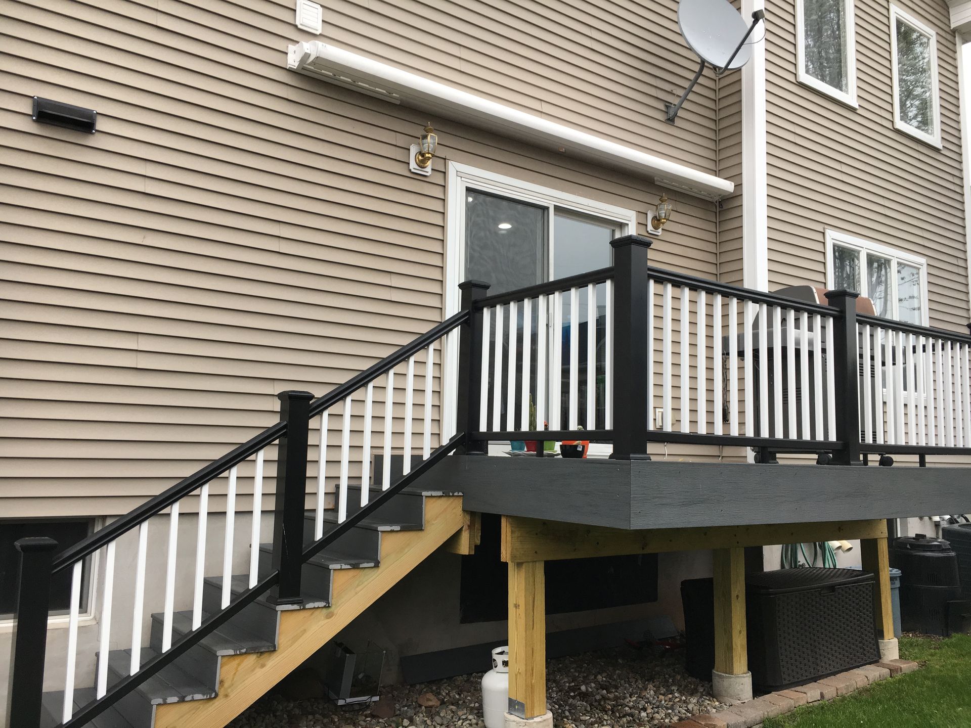 A deck with stairs leading up to it is in front of a house - Freehold, NJ - Awning Design Inc