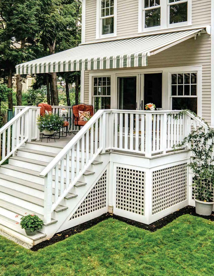 A white house with a striped awning on the porch - Freehold, NJ - Awning Design Inc