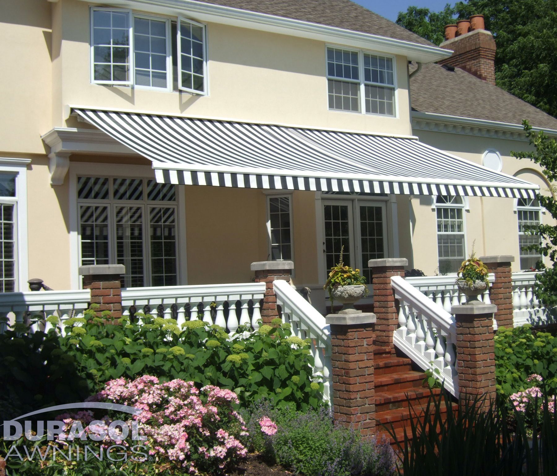 A white house with a black and white awning on the porch - Freehold, NJ - Awning Design Inc