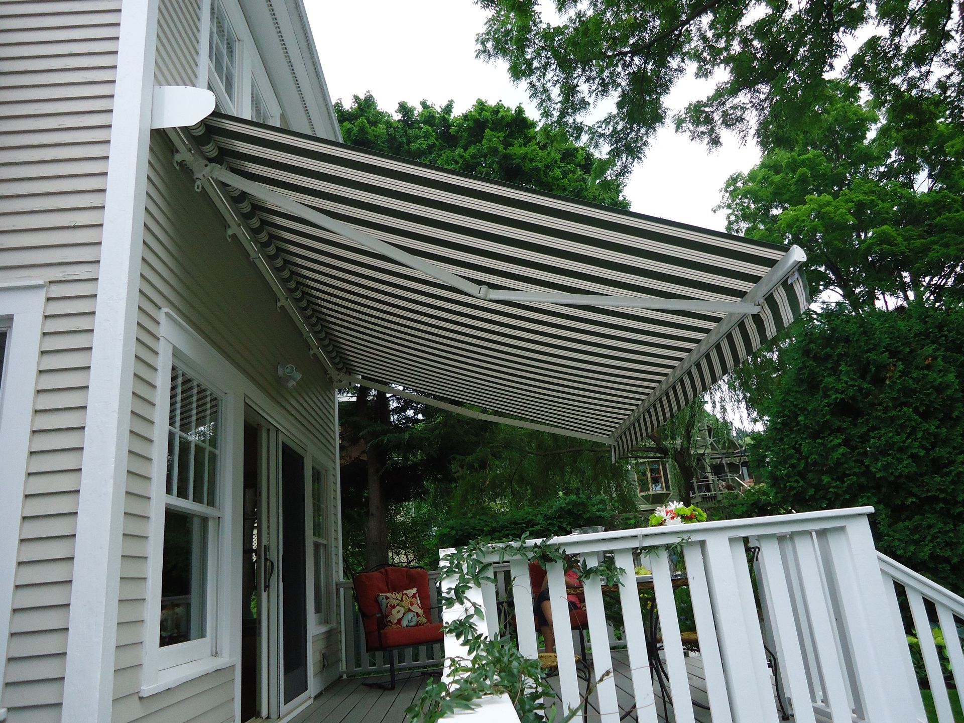 A house with a black and white awning over the deck - Freehold, NJ - Awning Design Inc