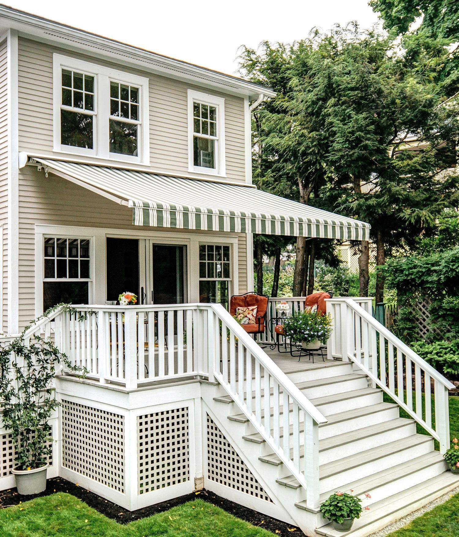 A balcony with a striped awning and a red chair - Freehold, NJ - Awning Design Inc