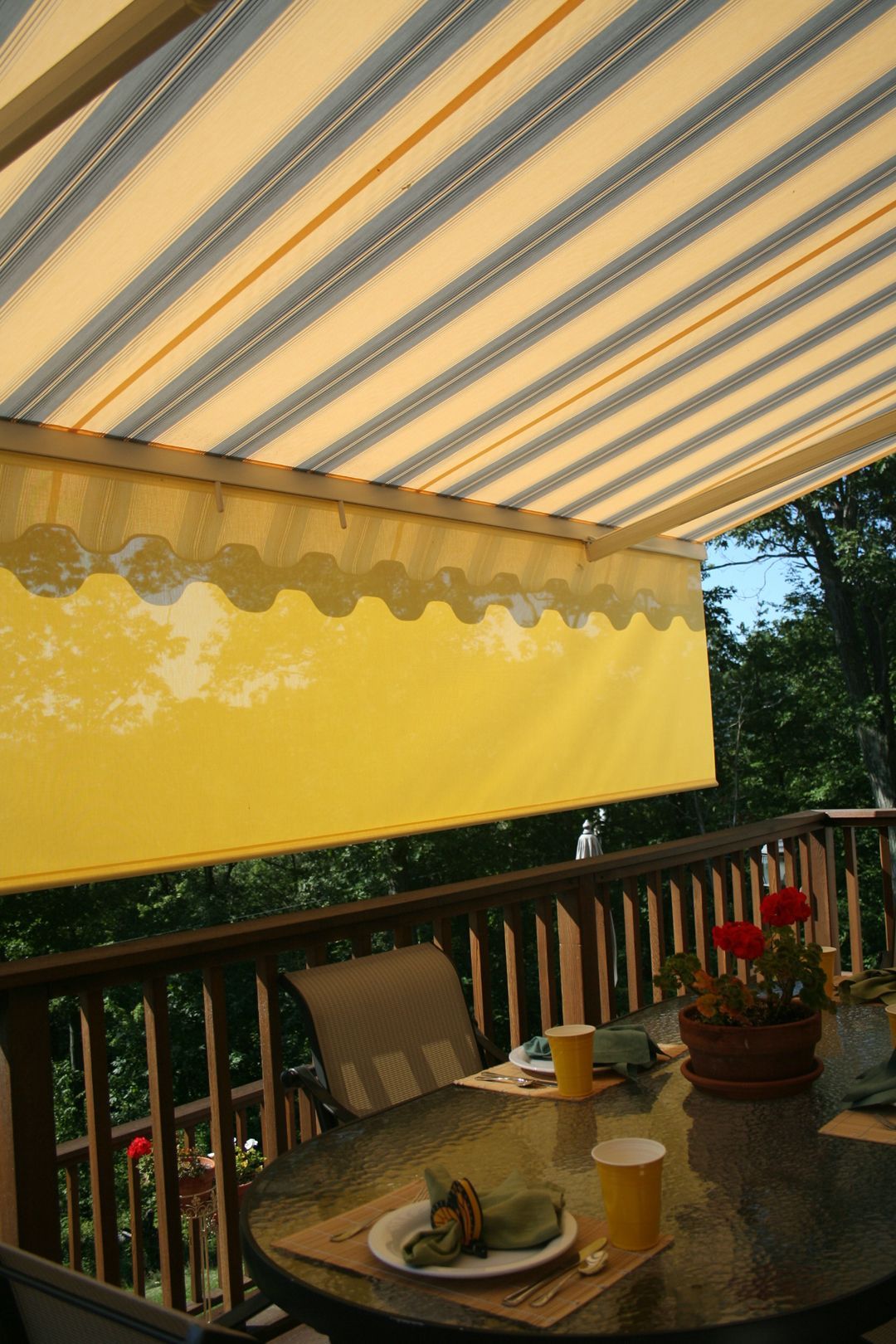 A table and chairs on a deck with a yellow awning - Freehold, NJ - Awning Design Inc