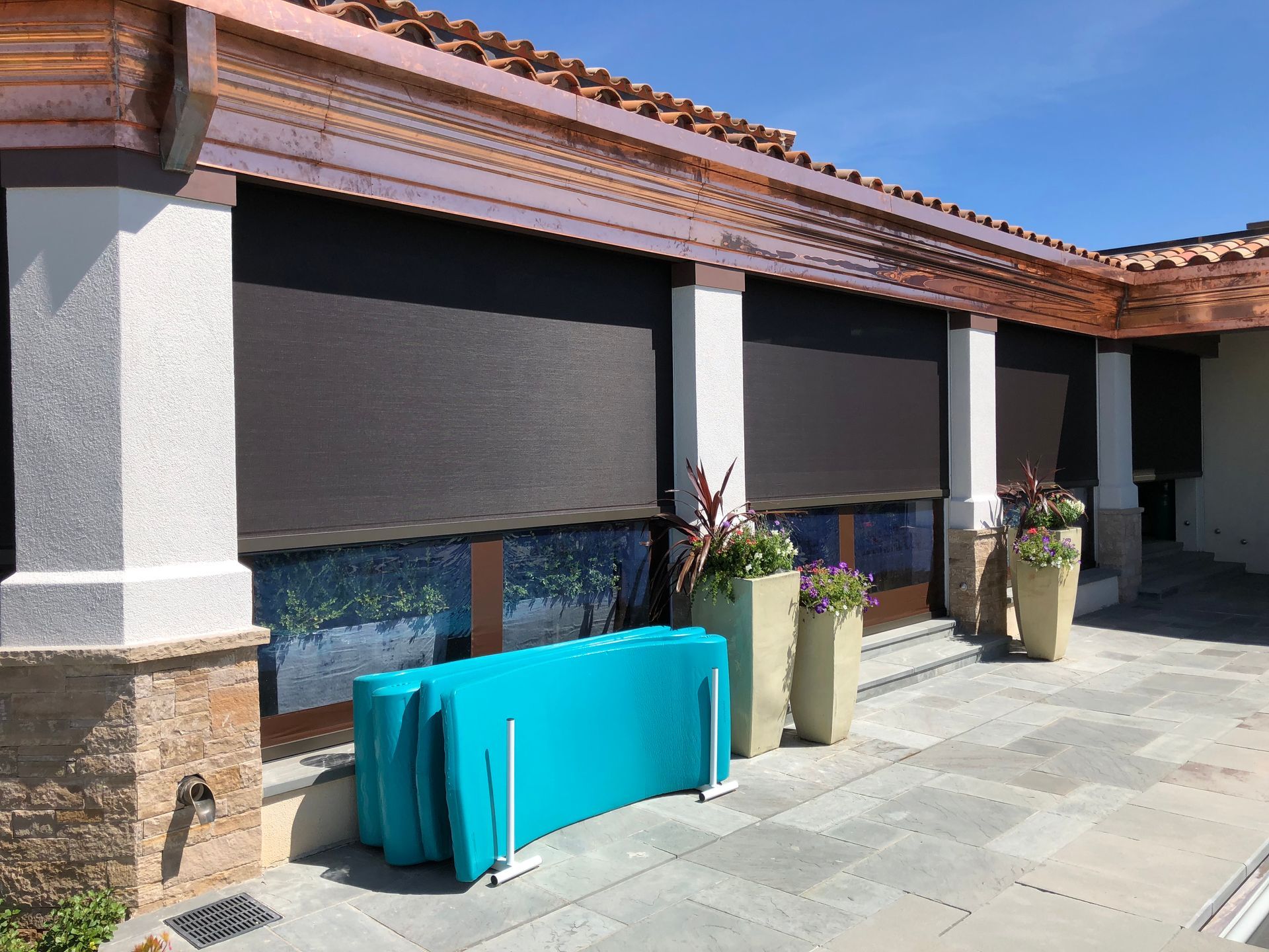 A blue couch is sitting on a patio in front of a building with a lot of windows - Freehold, NJ - Awning Design Inc