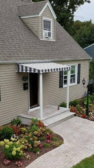 A house with a porch and a black and white awning on it - Freehold, NJ - Awning Design Inc