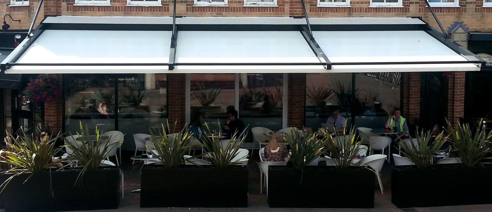 A restaurant with tables and chairs under a white awning - Freehold, NJ - Awning Design Inc