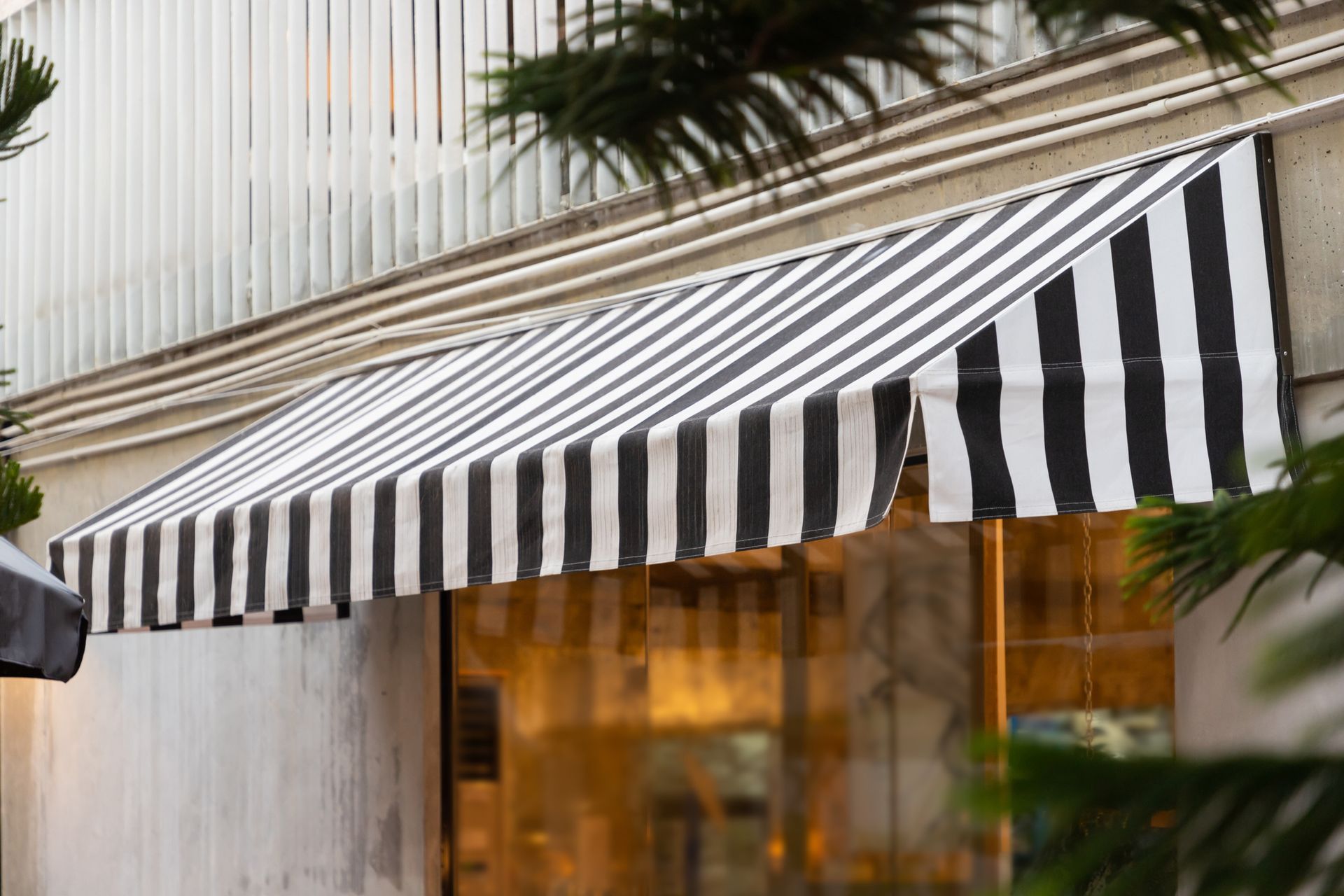 Black and white commercial awnings over shop window for business signage, shade, and curb appeal.