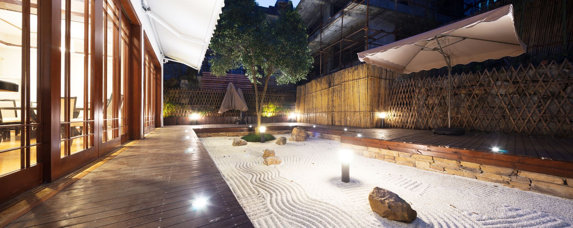 Modern terrace with wooden deck, lounge chair, and retractable awnings at dusk. Modern terrace with wooden deck, lounge chair, and retractable awnings at dusk.