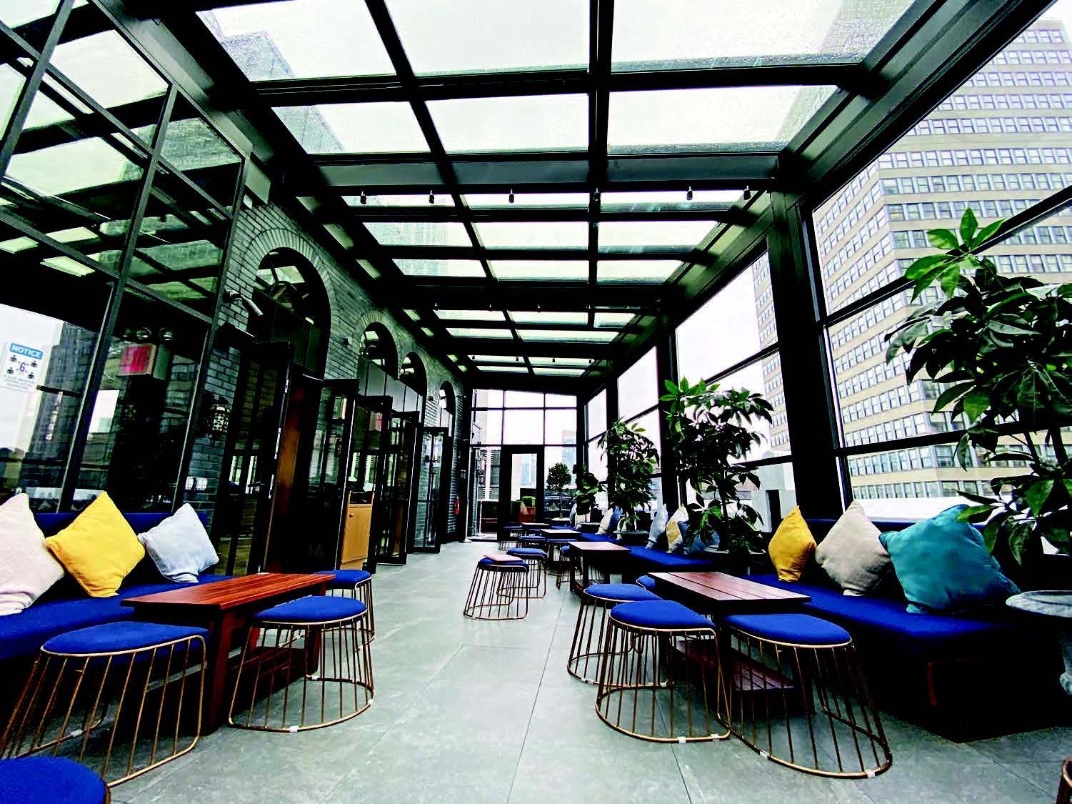 A restaurant with tables and chairs under a glass roof - Freehold, NJ - Awning Design Inc