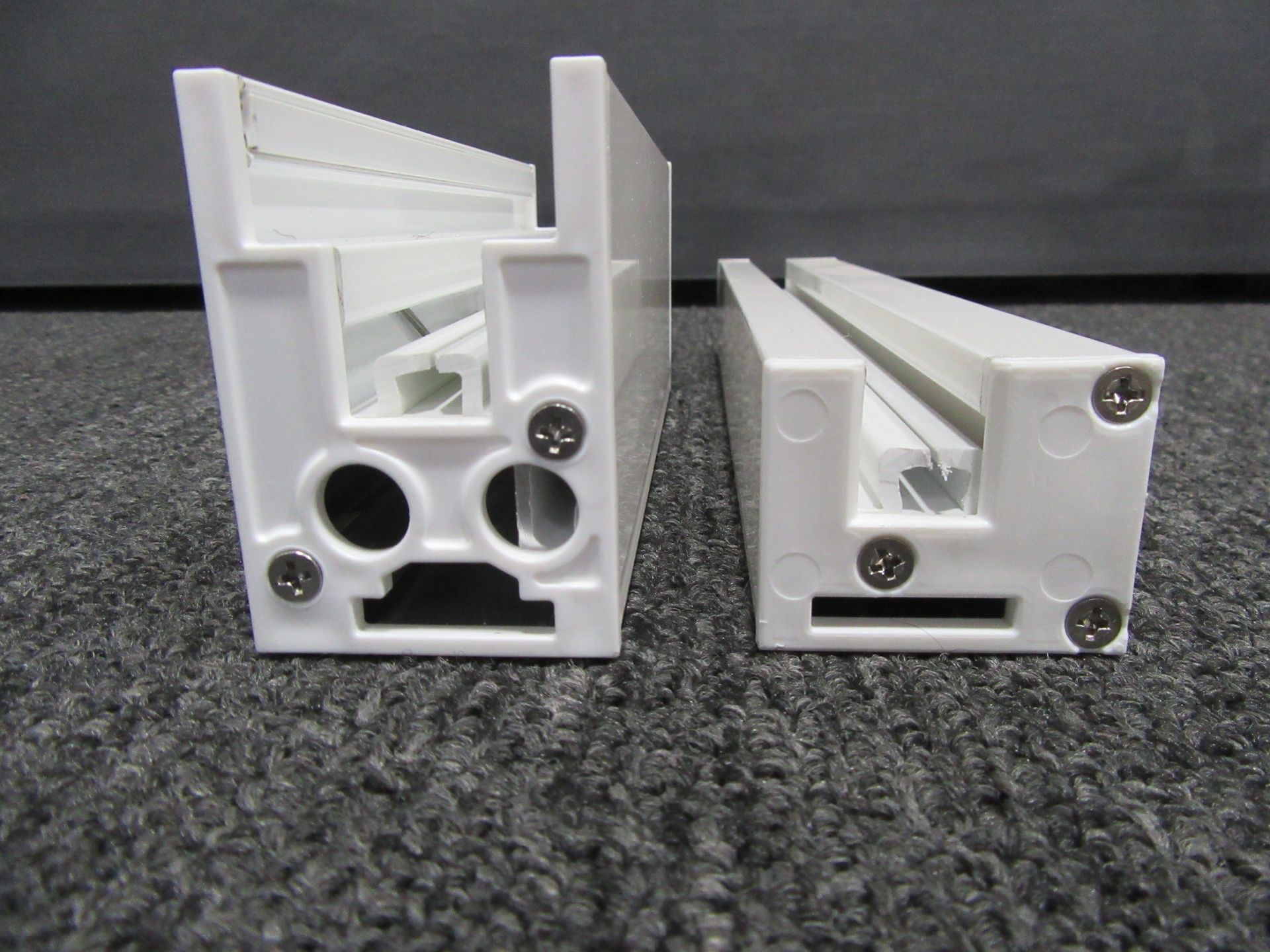 Two white plastic pieces with screws on them are sitting on a carpet - Freehold, NJ - Awning Design Inc