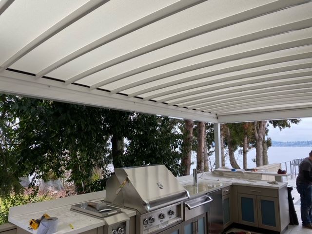 A man is standing in a kitchen with a grill under a canopy - Freehold, NJ - Awning Design Inc