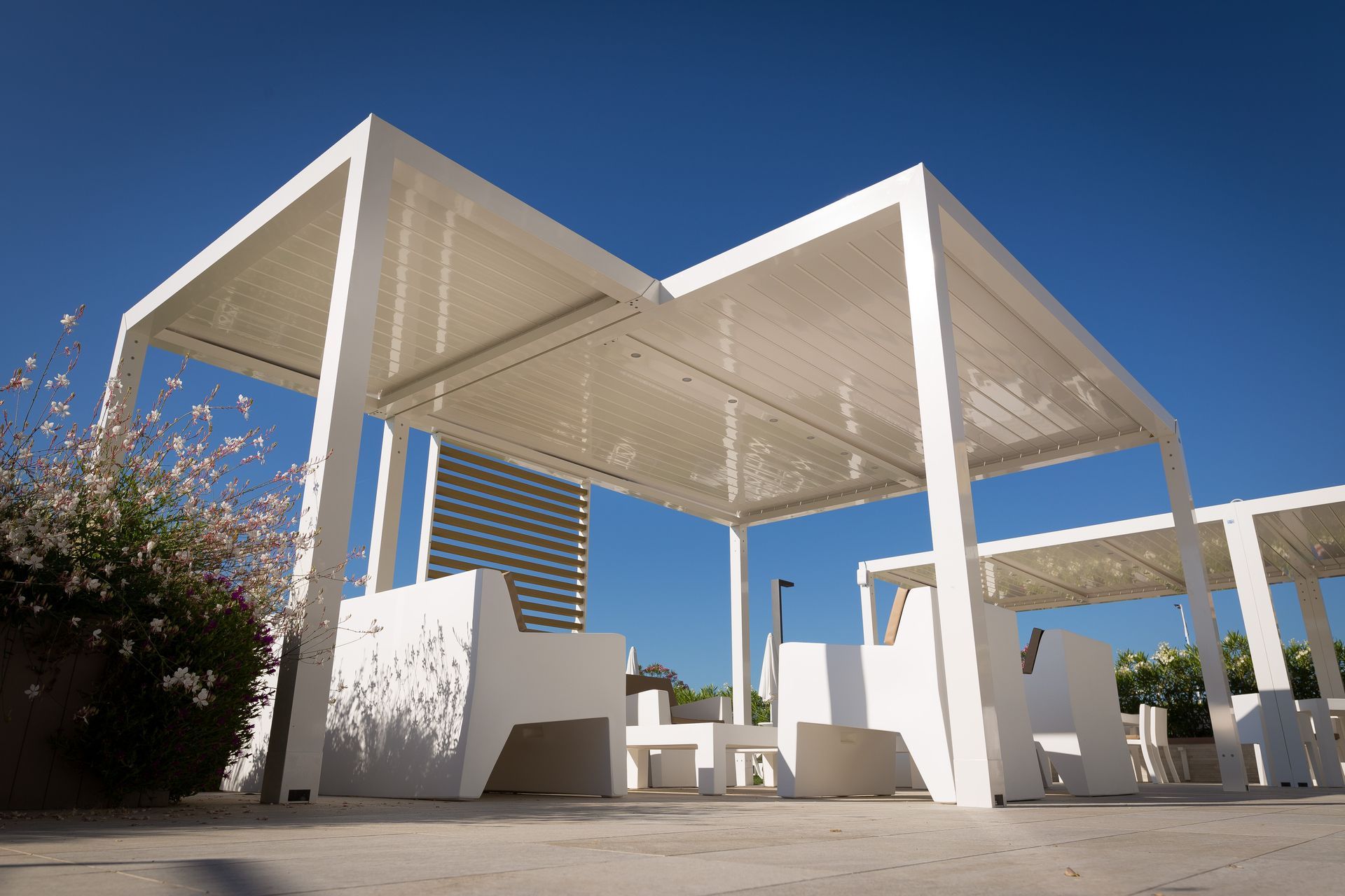 A white pergola with a table and chairs underneath it - Freehold, NJ - Awning Design Inc