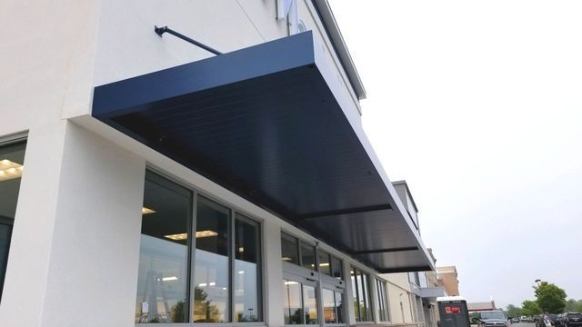 A blue awning is on the side of a building - Freehold, NJ - Awning Design Inc