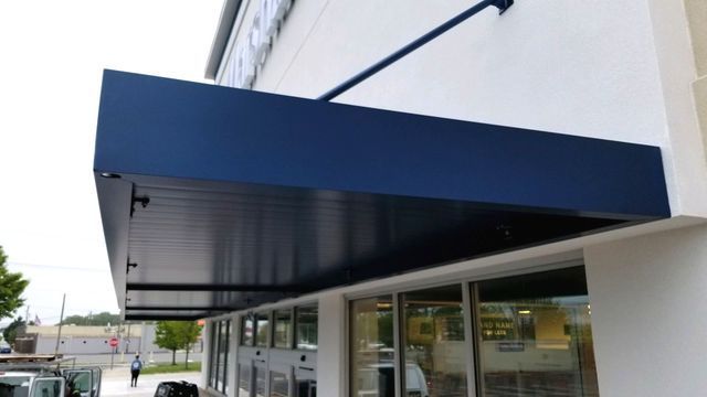 A blue awning is on the side of a building - Freehold, NJ - Awning Design Inc