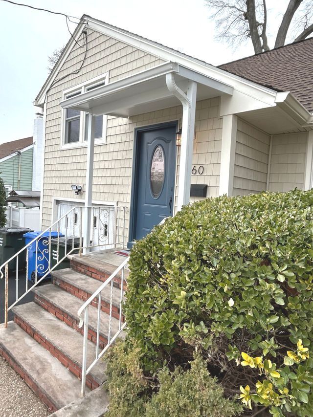 A house with a blue door and stairs leading up to it - Freehold, NJ - Awning Design Inc