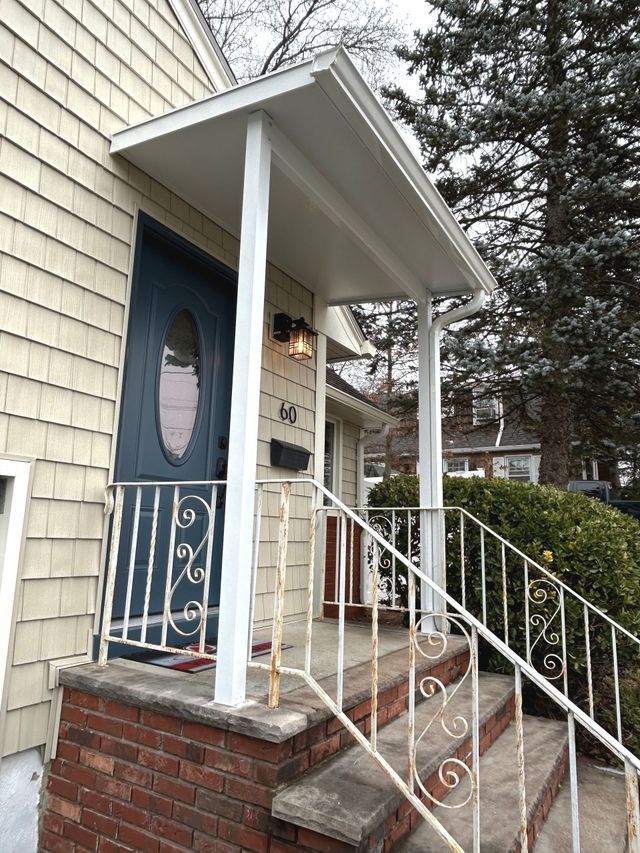 A house with a porch and stairs and a blue door - Freehold, NJ - Awning Design Inc