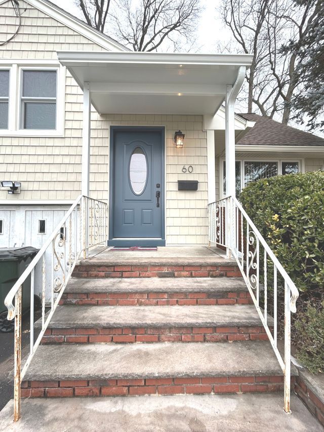 The front door of a house with a blue door and stairs leading up to it - Freehold, NJ - Awning Design Inc