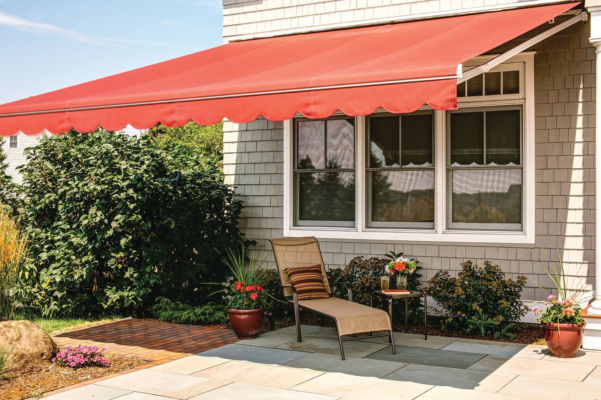 A white house with a red awning over a patio - Freehold, NJ - Awning Design Inc