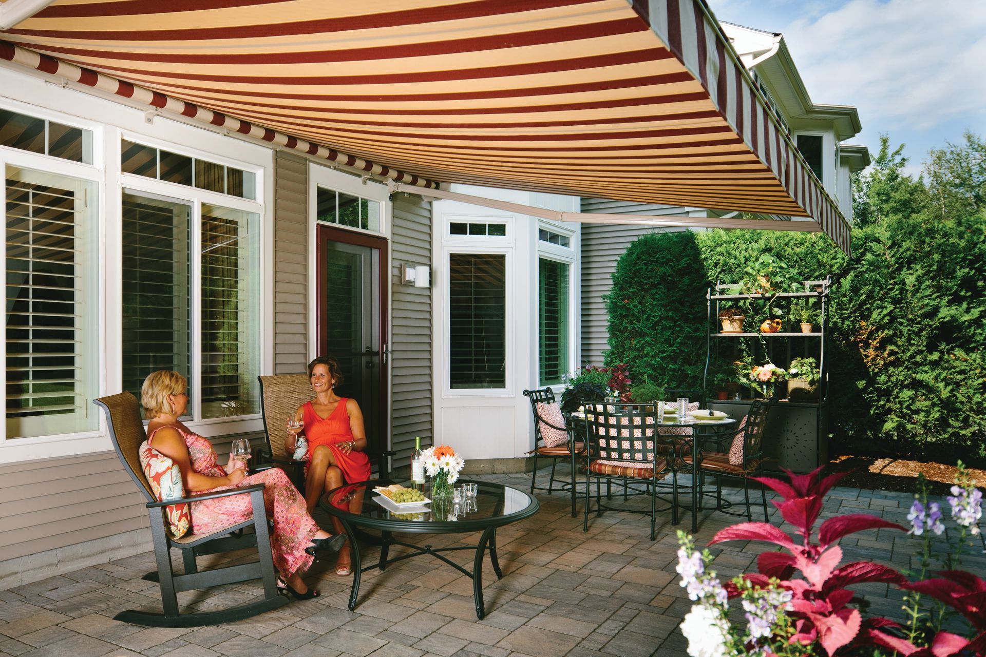 Two women are sitting under an awning on a patio - Freehold, NJ - Awning Design Inc