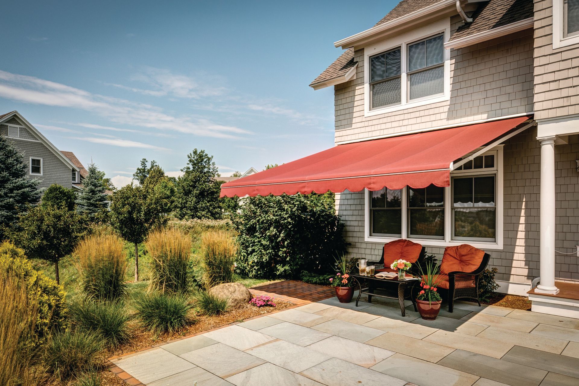 A house with a red awning over a patio with furniture - Freehold, NJ - Awning Design Inc