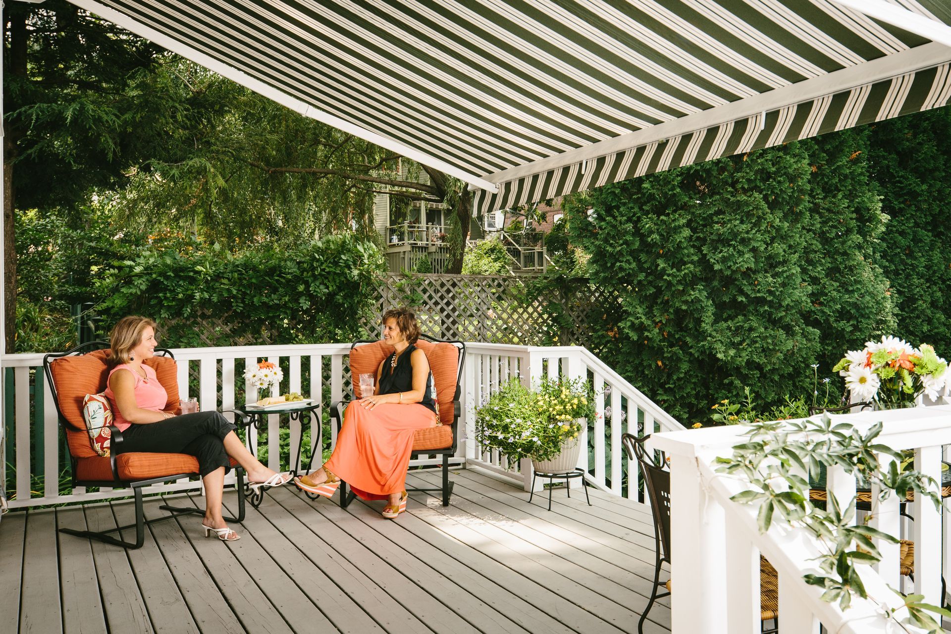 Two women are sitting on a deck under an awning - Freehold, NJ - Awning Design Inc