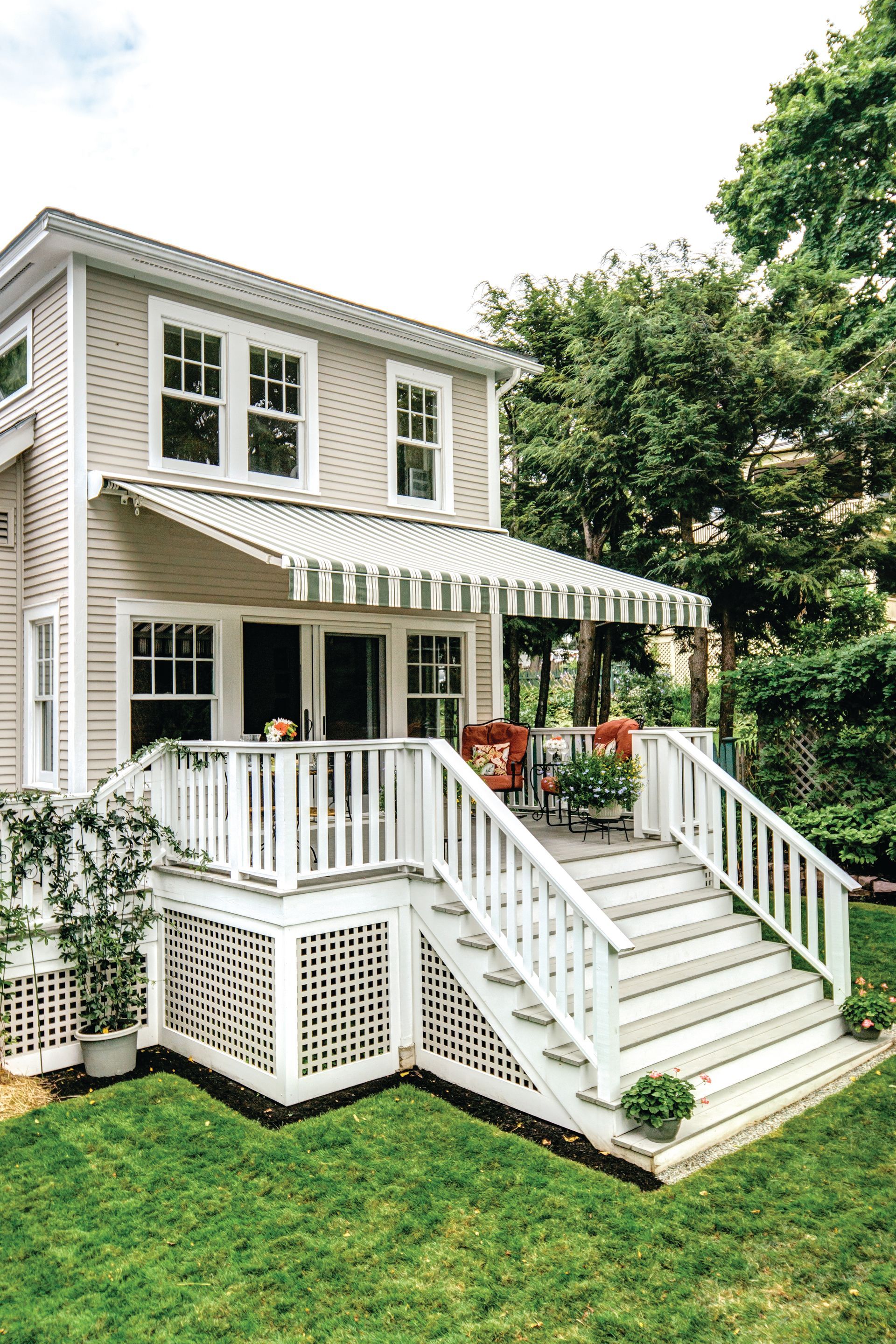 A house with a striped awning on the porch and stairs leading up to it - Freehold, NJ - Awning Design Inc