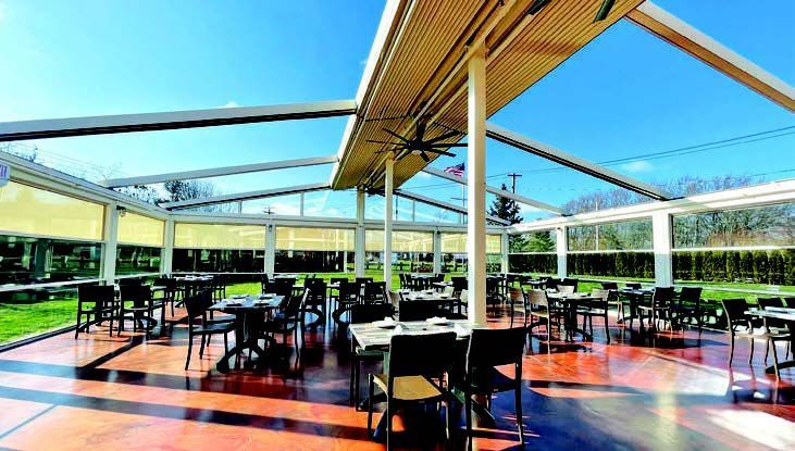 A restaurant with tables and chairs under a clear roof - Freehold, NJ - Awning Design Inc