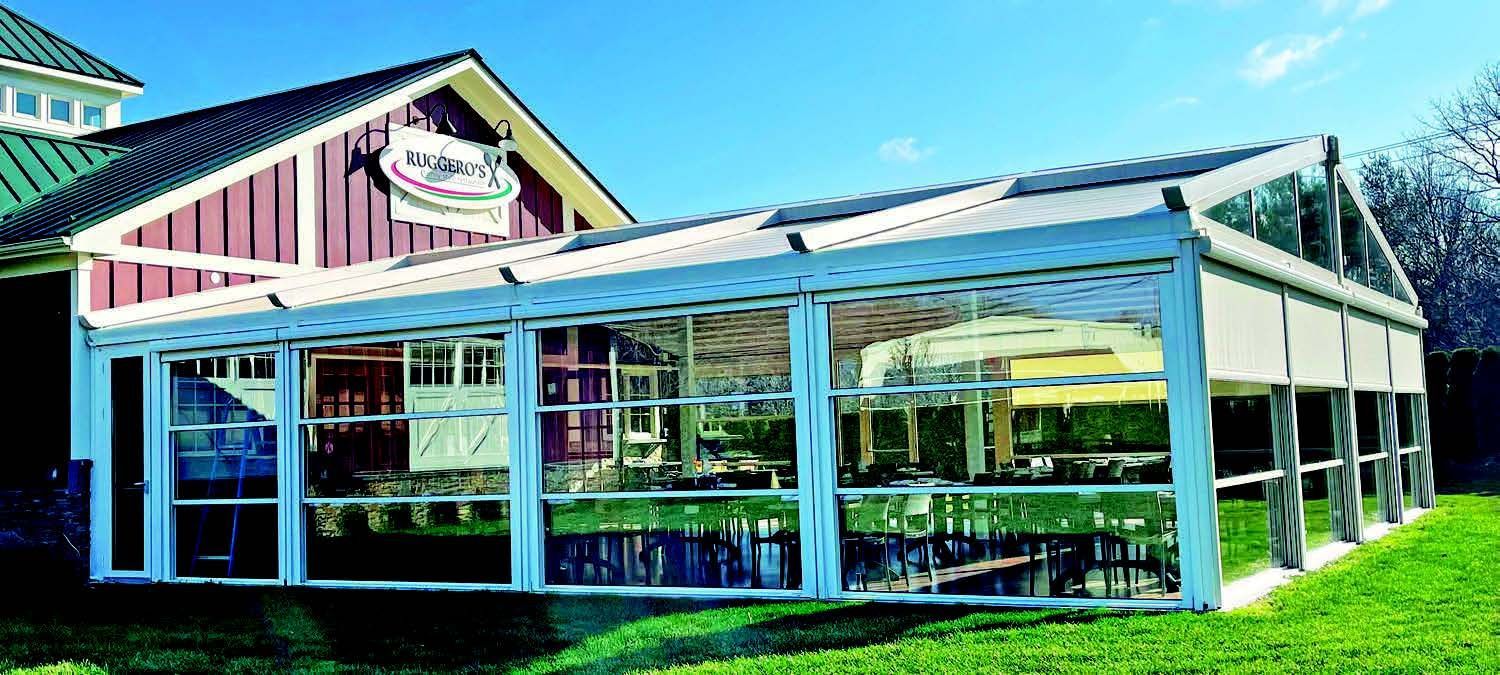 A large building with a lot of windows is sitting on top of a lush green field - Freehold, NJ - Awning Design Inc