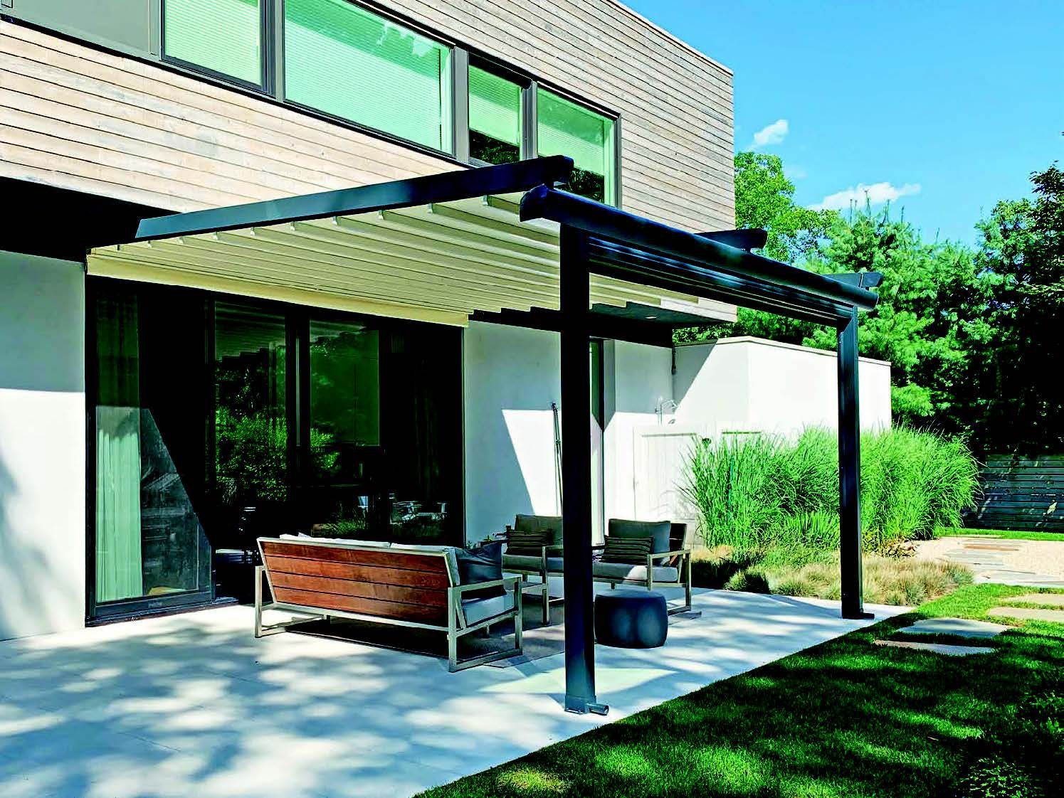 A patio with a pergola and a couch in front of a house - Freehold, NJ - Awning Design Inc