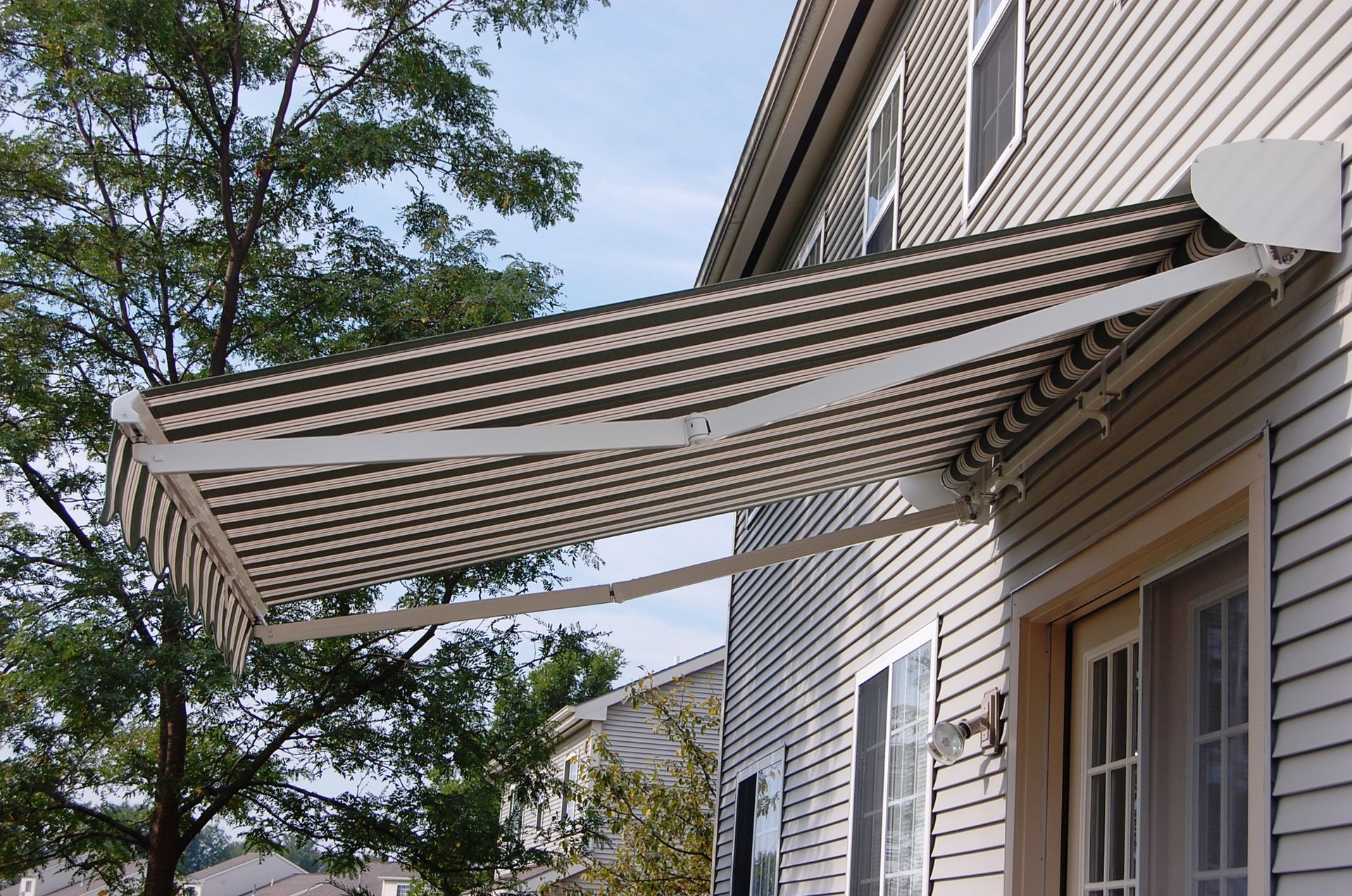 A house with a striped awning over the front door - Freehold, NJ - Awning Design Inc