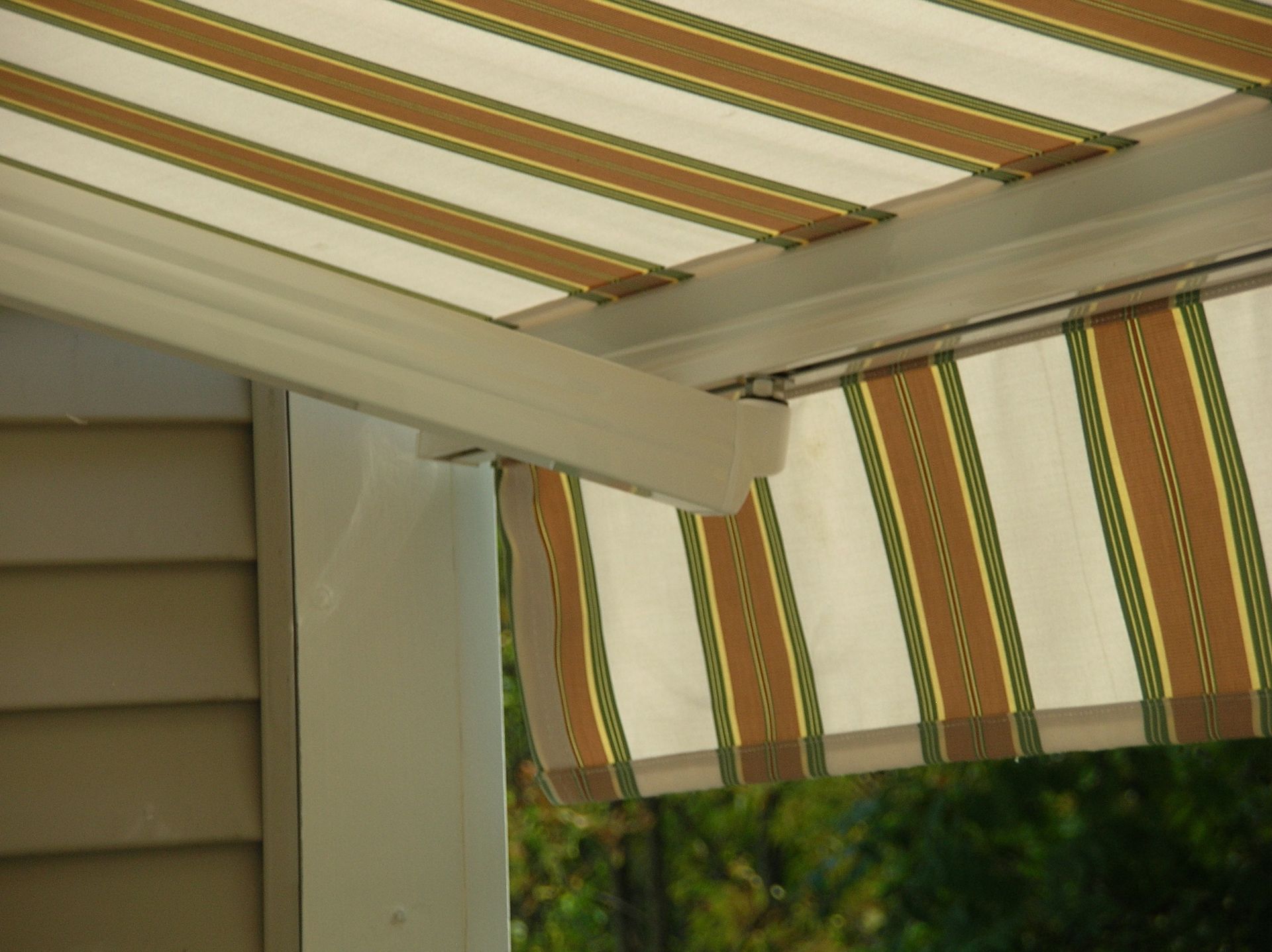 A striped awning is hanging from the side of a house - Freehold, NJ - Awning Design Inc