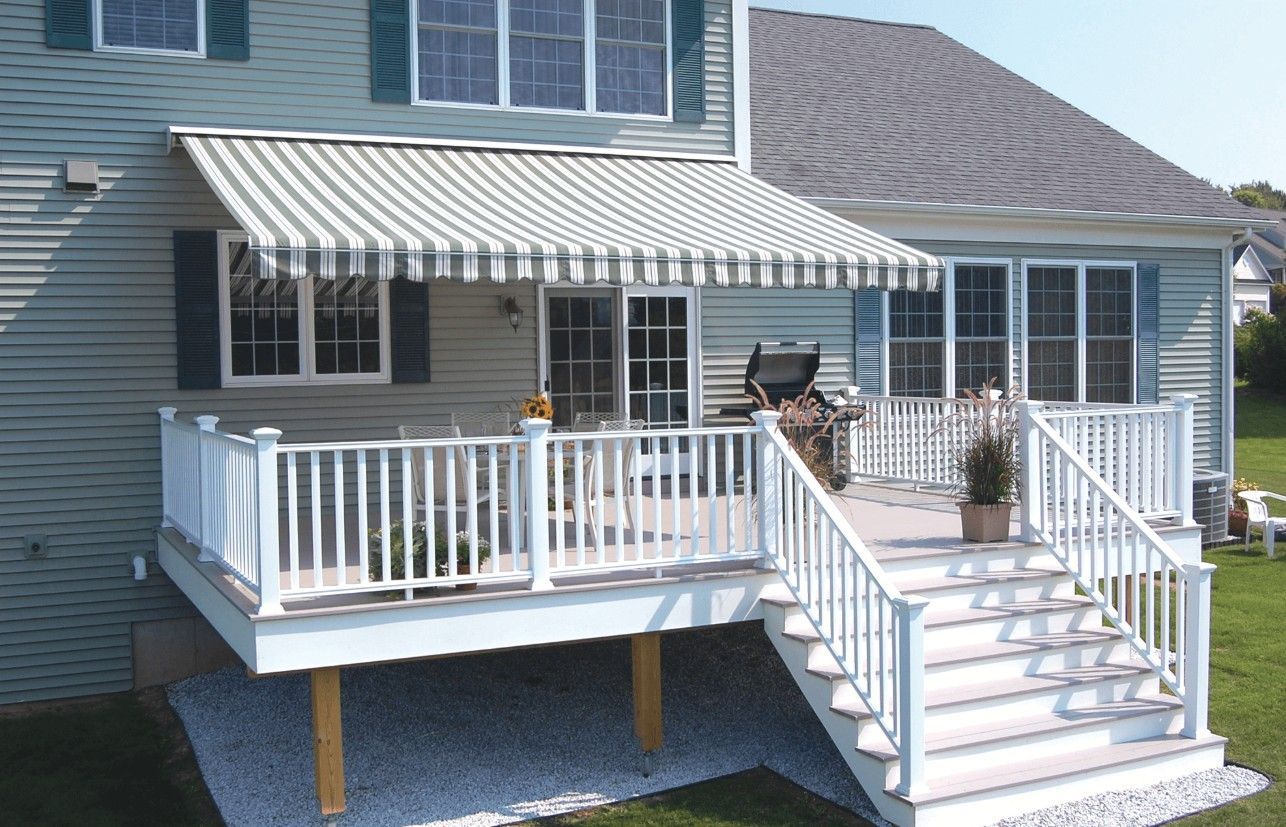 Modern terrace with wooden deck, lounge chair, and retractable awnings at dusk. Modern terrace with wooden deck, lounge chair, and retractable awnings at dusk.