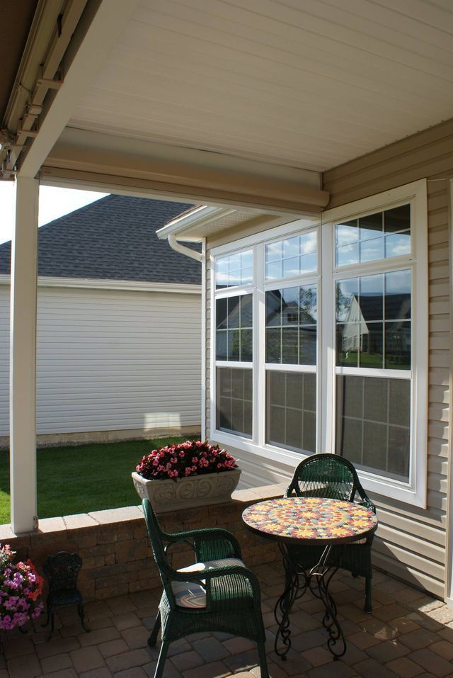 There is a table and chairs on the porch of a house - Freehold, NJ - Awning Design Inc