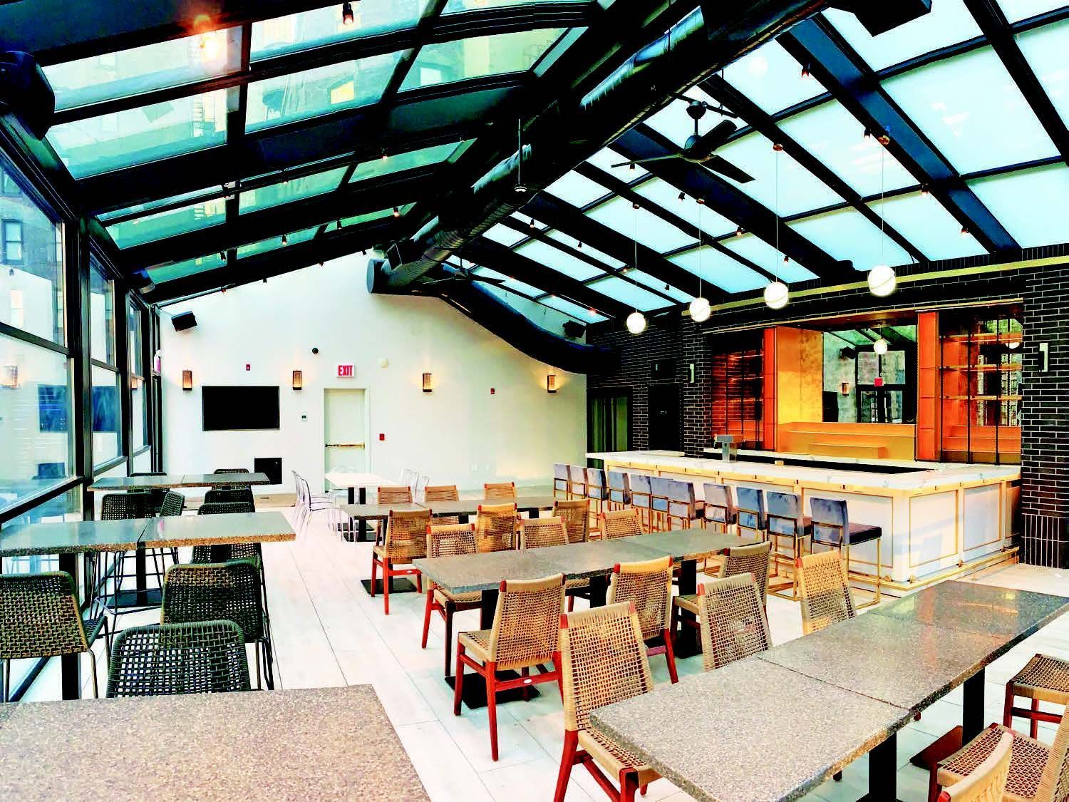 A restaurant with tables and chairs under a glass roof - Freehold, NJ - Awning Design Inc