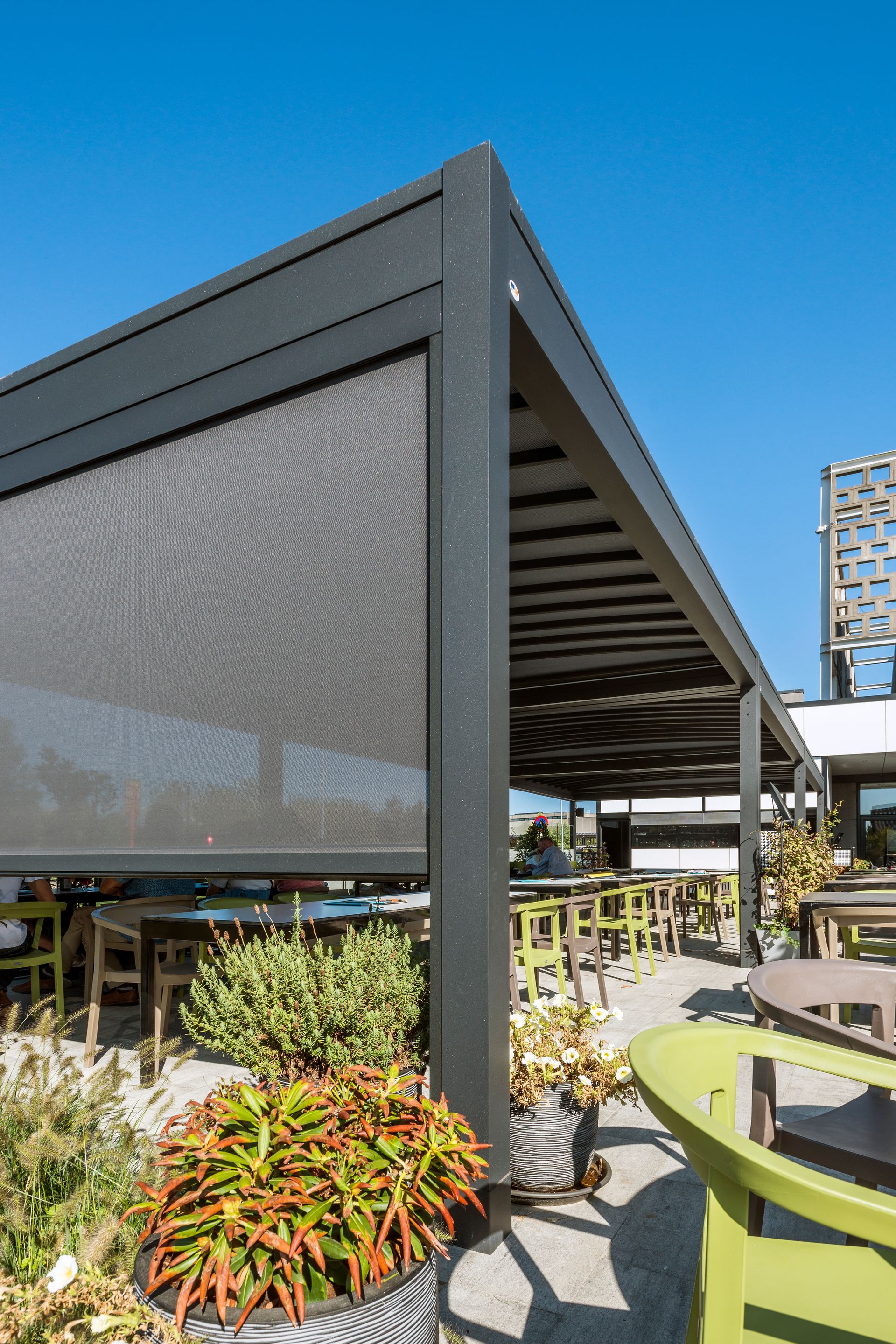 A patio with tables and chairs under a canopy with a screen - Freehold, NJ - Awning Design Inc