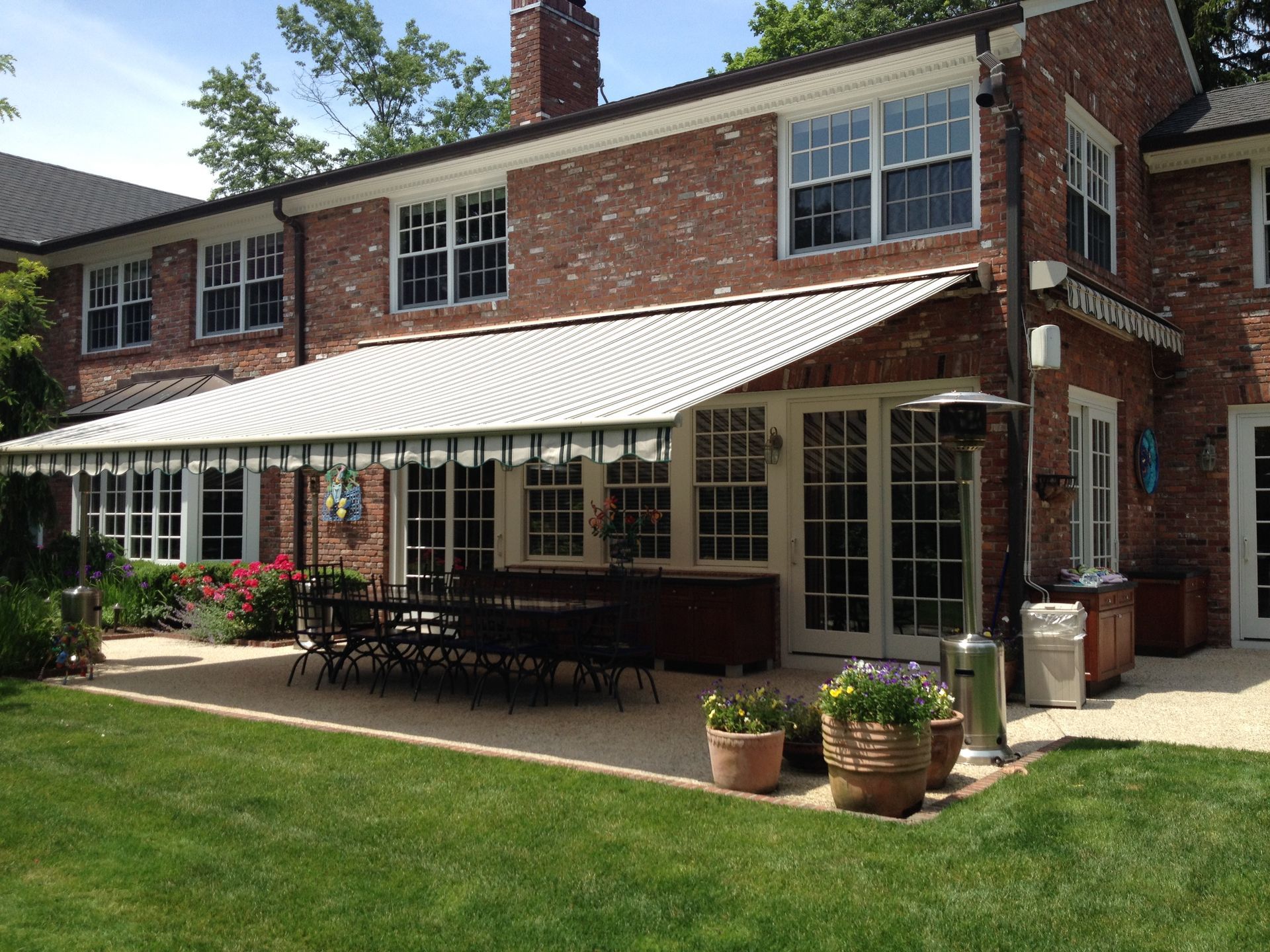 A large brick house with a large awning over the patio - Freehold, NJ - Awning Design Inc