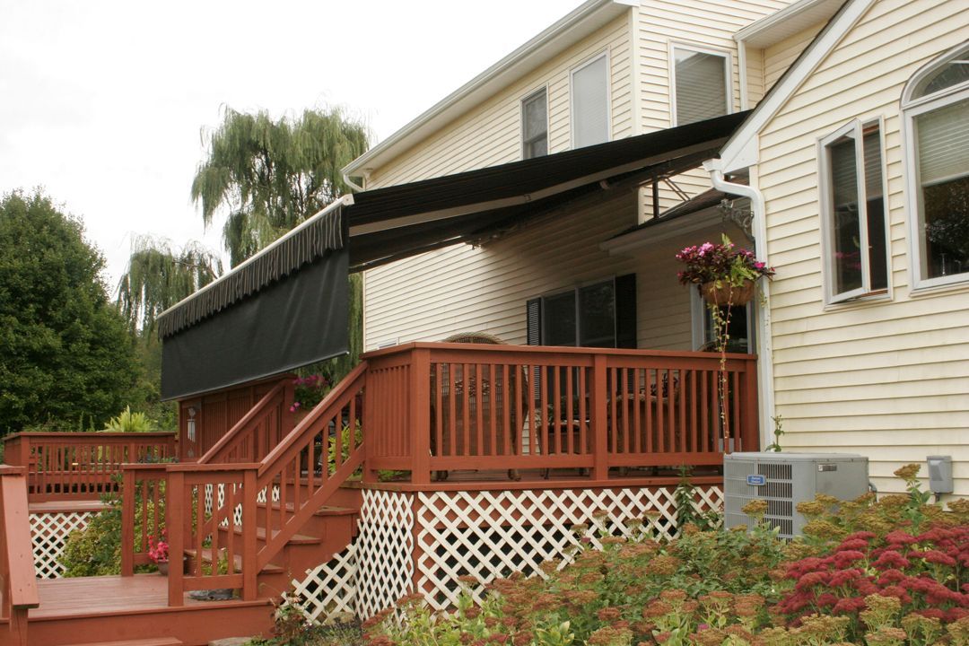 A white house with a red deck and a black awning - Freehold, NJ - Awning Design Inc