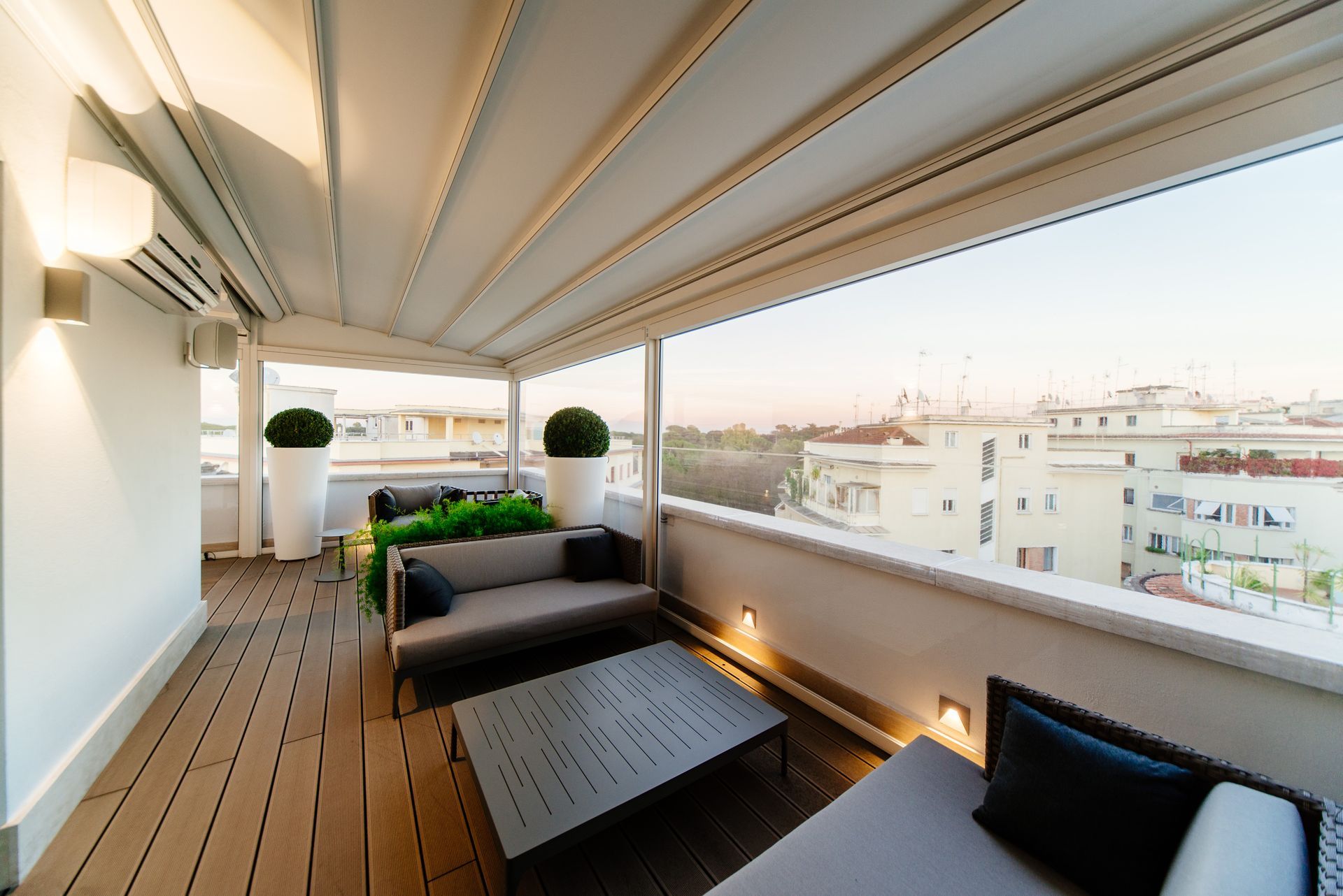 A balcony with a couch and a table with a view of the city - Freehold, NJ - Awning Design Inc