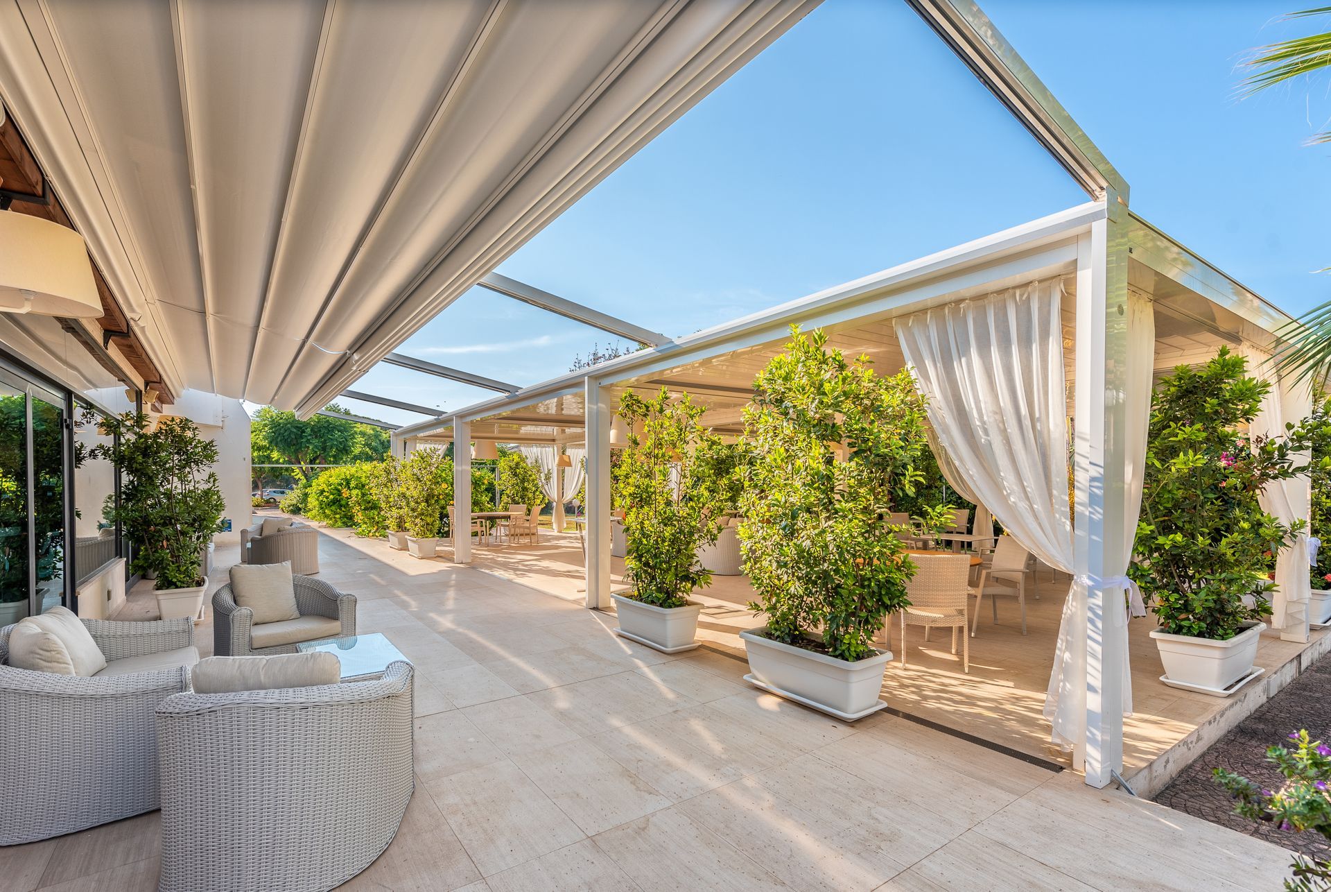 A patio with wicker furniture and plants under a canopy - Freehold, NJ - Awning Design Inc