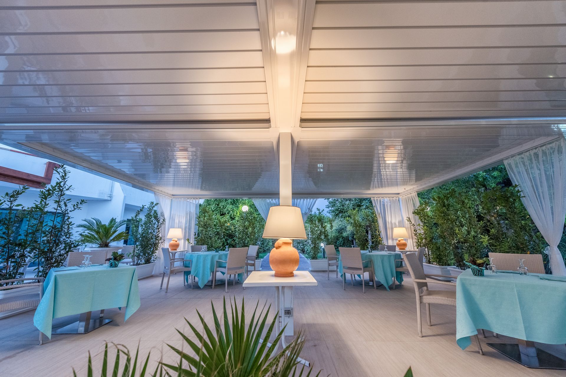 A restaurant with tables and chairs under a canopy with a lamp on a table - Freehold, NJ - Awning Design Inc