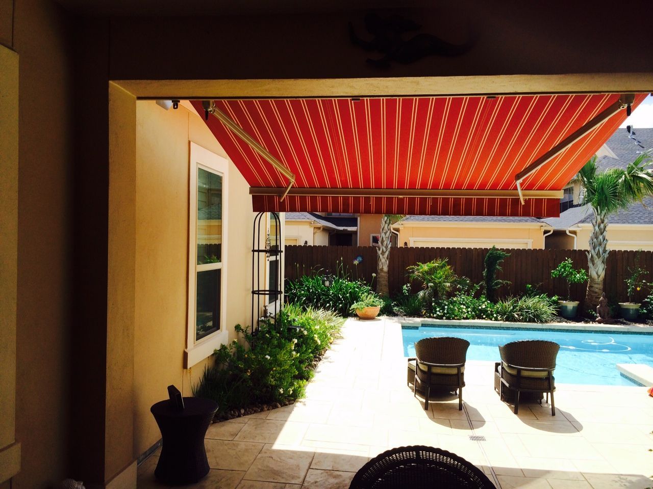 A patio with a red awning over a swimming pool - Freehold, NJ - Awning Design Inc