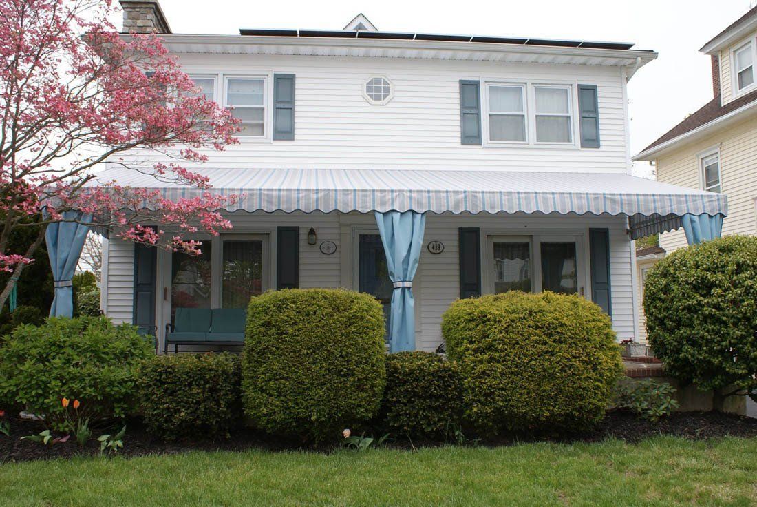 A white house with a blue awning on the porch