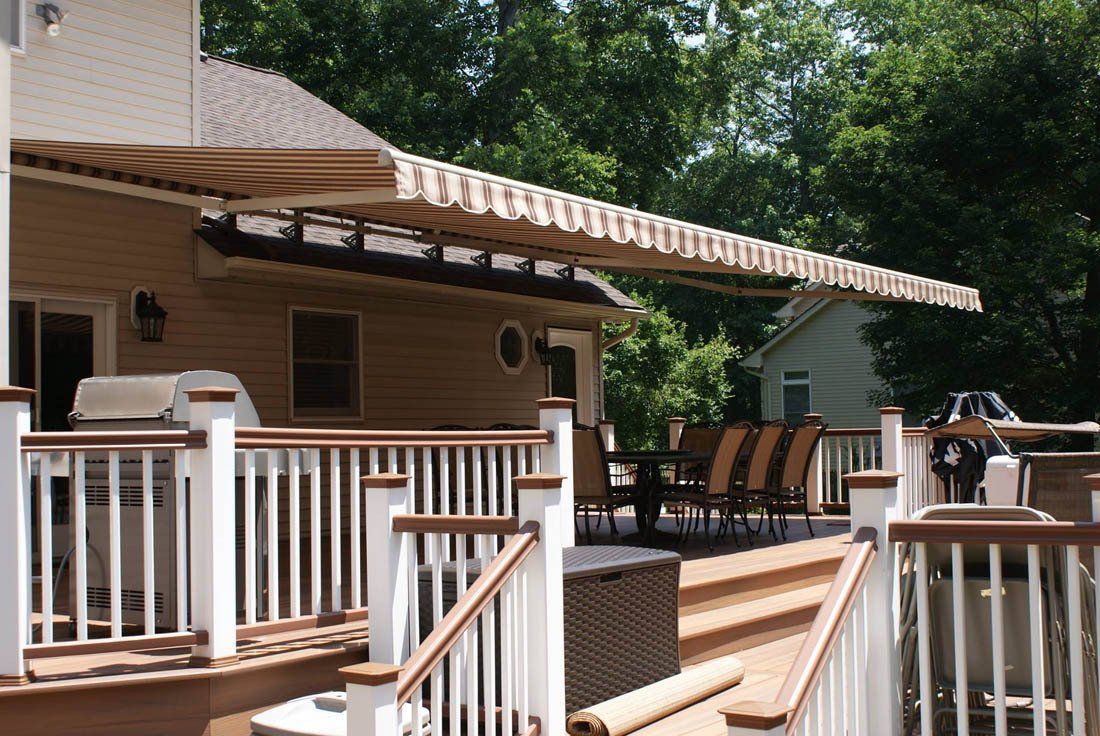 A deck with a white railing and an awning over it