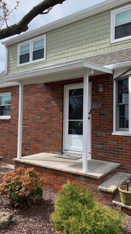 A brick house with a porch and a white door - Freehold, NJ - Awning Design Inc