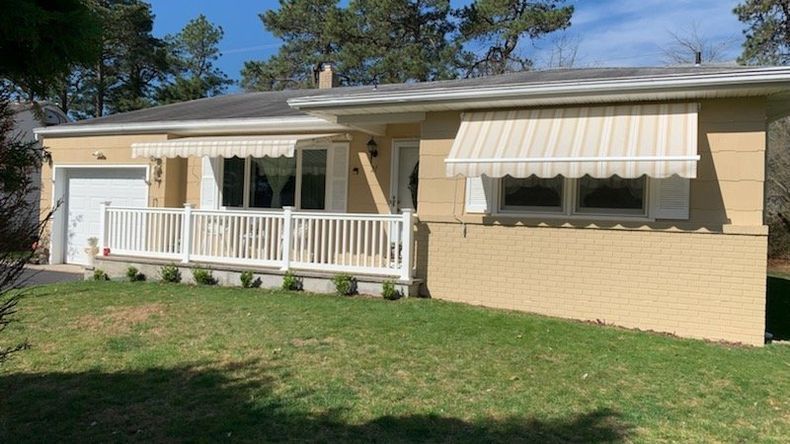 A house with a white awning on the front of it - Freehold, NJ - Awning Design Inc